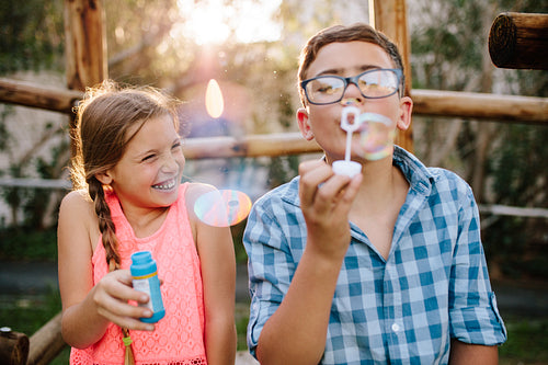 Young boy and girl having fun blowing soap bubbles
