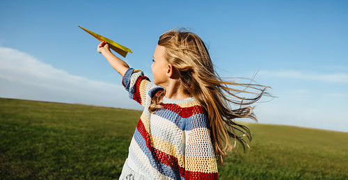 Young girl throws plane outdoors enjoying the breeze