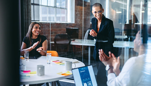 Happy young businesswoman being applauded by her team in an offi