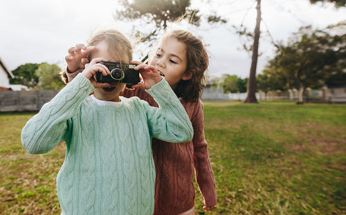 Little girls taking pictures with camera at the park