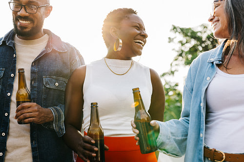 Diverse colleagues bonding over drinks and laughter outdoors on a sunny day