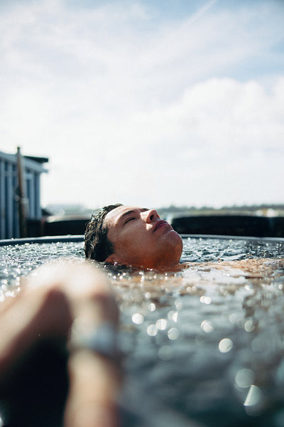 A submerged recovery scene features a man relaxing in an outdoor ice bath.