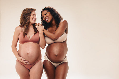 Expecting happiness: Two smiling mothers embracing maternity in the third trimester of pregnancy