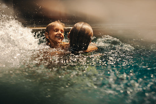 Fun family vacation in swimming pool with happy child enjoying the water splash