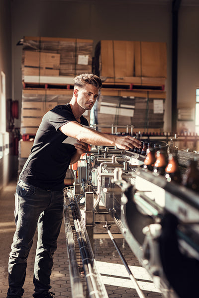 Young man supervising the beer bottling process