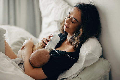 Mother feeding baby early in morning on bed