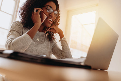 Businesswoman working from home on laptop and mobile phone
