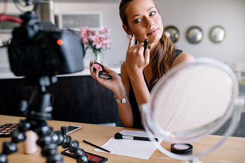 Young female vlogger recording a make-up video for her vlog.
