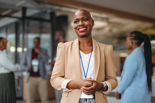 Professional businesswoman smiling in office environment with colleagues in background