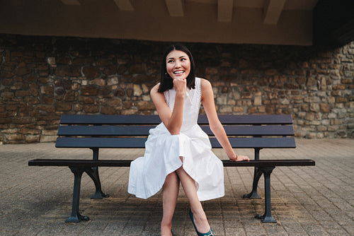 Thoughtful female student sitting on a bench outdoors