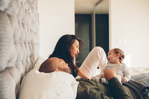 Parents with little baby boy on bed