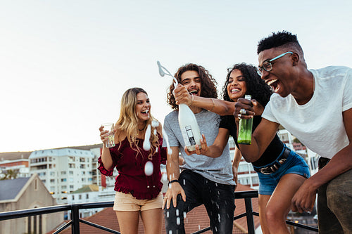 Friends having opening champagne bottle at party