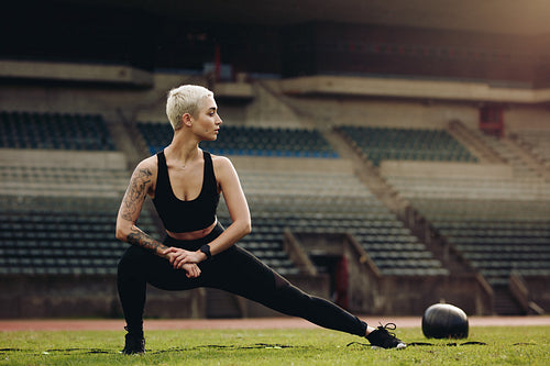 Woman athlete doing stretching exercises in a stadium