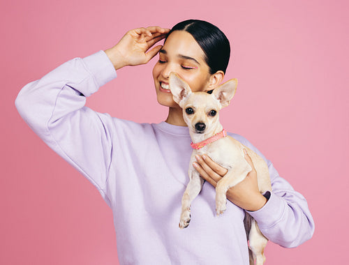 Cuteness in the studio: Happy woman holding a cute puppy in a studio