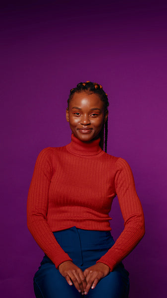 Young woman smiles at camera against purple background