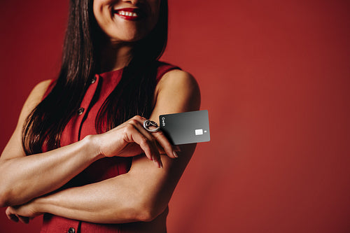 Woman holding credit card in banking studio portrait with confident smile