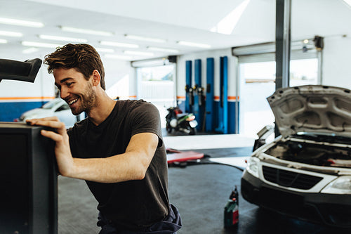 Smiling mechanic doing car diagnostic on computer