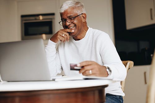 Carefree senior man shopping online at home