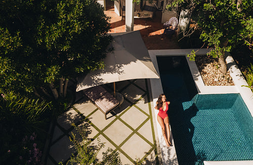 Top view of a young woman relaxing on the edge of a pool