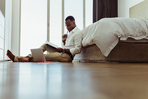 Man taking notes whilst working from home on his laptop