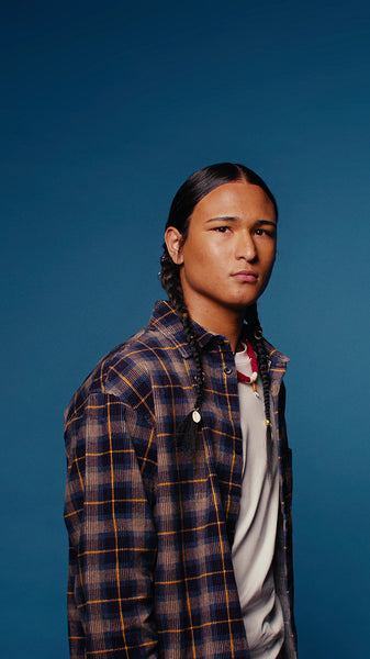 Young man with braids posing in studio against blue background