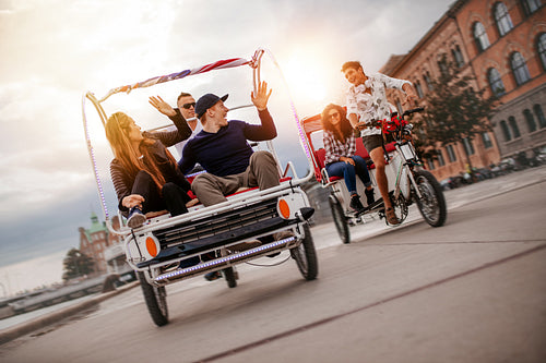 Group of friends having fun with two tricycles on road