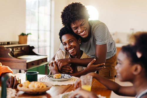 Happy son hugging his mom during a family breakfast in a Brazilian home