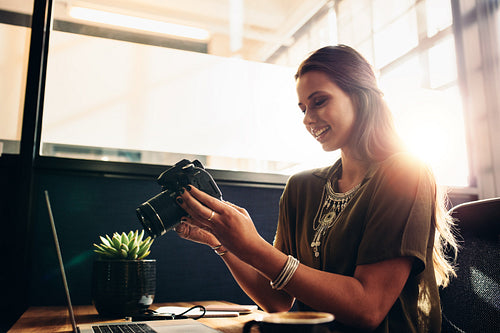 Young female photographer watching her camera while editing her vlog on computer.