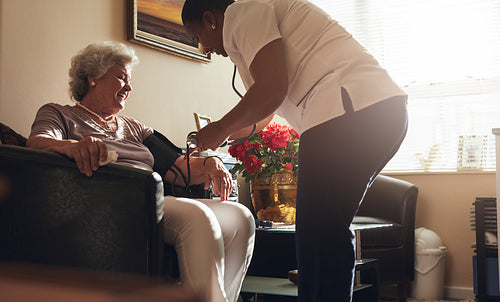 Female healthcare worker taking blood pressure of senior patient