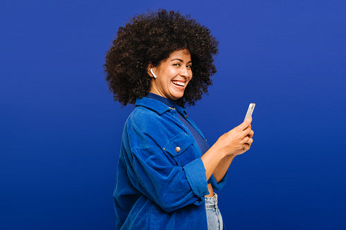 Happy young woman playing her favourite music on a smartphone