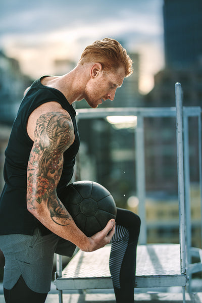 Fitness man doing workout on rooftop using a medicine ball