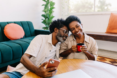 Couple enjoying quality time at home, relaxing and browsing a smartphone