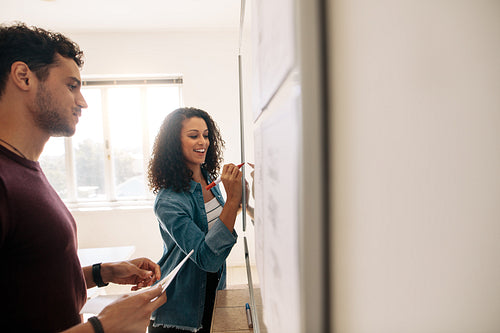 Woman entrepreneur writing on whiteboard in office