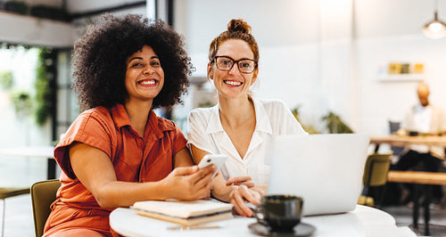 Team building over coffee: Two happy women working in a cafe