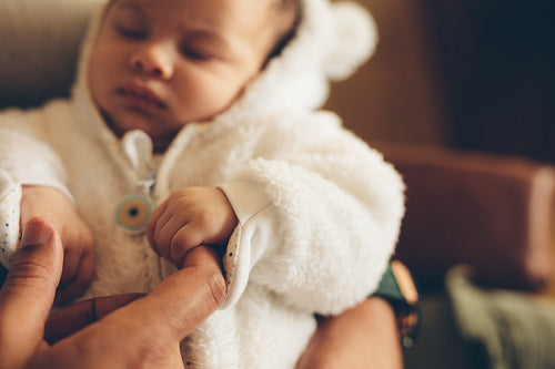 Newborn baby holding father's finger