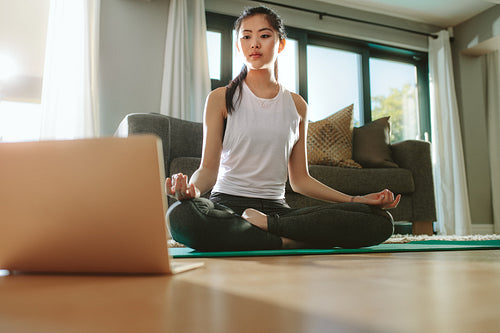 Girl looking at laptop and doing yoga at home
