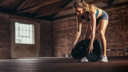 Athlete preparing weights for exercising at fitness club
