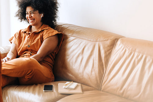 Cheerful female entrepreneur taking a phone call using wireless earphones
