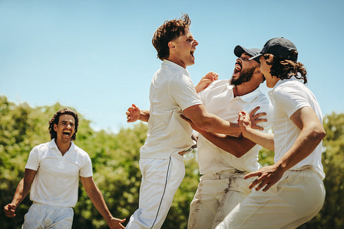 Young male cricket players celebrating a significant victory on the field