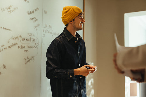 Presenting meeting ideas at the whiteboard with a coworker in the office