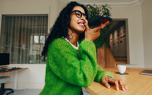 The woman handles customer service communication on a smartphone at her workspace