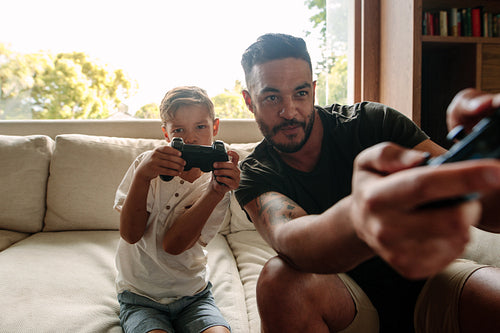 Father and son playing video game at home