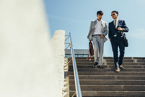 Business men talking and walking down the steps