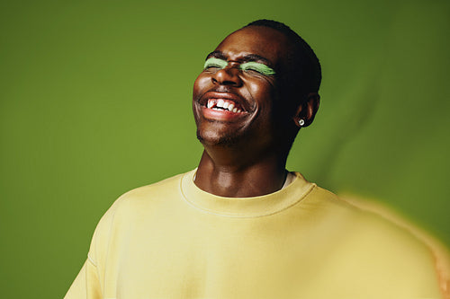 Man portrait laughing in studio with bold makeup and expressive style