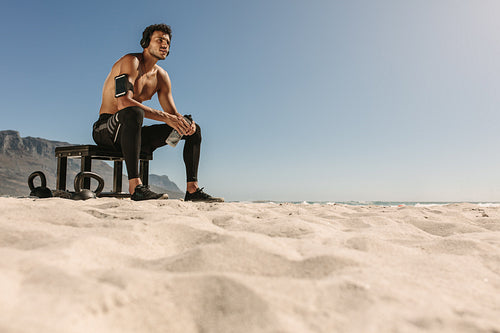 Man relaxing after workout on the beach drinking water