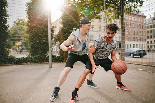 Teenagers playing basketball on outdoor court 