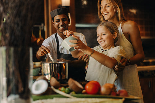 Chef guiding family cooking lesson with fresh ingredients in a cozy kitchen
