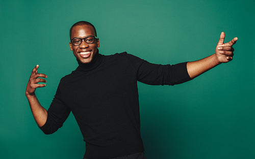 Confident smiling man in casual clothing strikes a stylish pose on green background