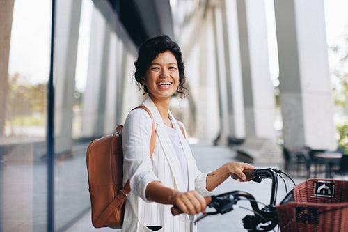 Happy woman smiling while riding bike with basket on street
