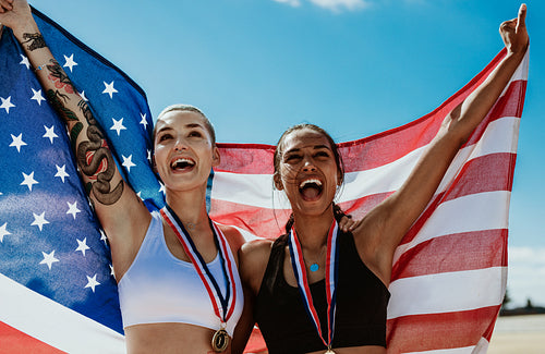 Female athletes celebrating victory holding american flag